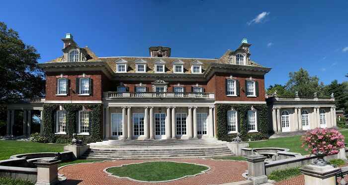 Large historic home with classic columns and brick facade, showcasing America’s architectural heritage in a serene garden setting.