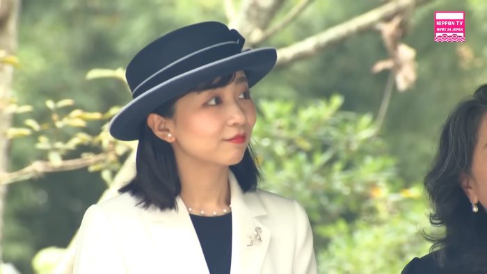Japanese Princess Kako wearing a black hat and white coat, attending an outdoor event with greenery in the background. Japanese Princess Kako wearing a black hat and white coat, attending an outdoor event with greenery in the background.
