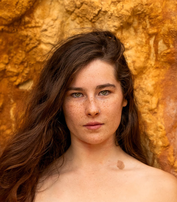 Gen Z woman with long hair and freckles standing against a textured orange background, symbolizing natural beauty and confidence. Gen Z woman with long hair and freckles standing against a textured orange background, symbolizing natural beauty and confidence.