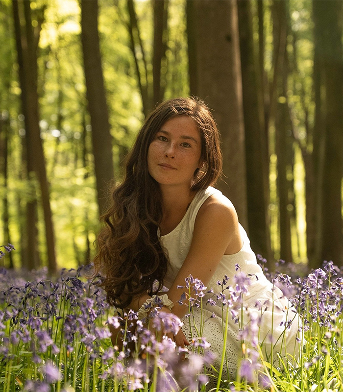 Gen Z woman with long hair sitting in a forest surrounded by purple flowers, embracing natural beauty and body hair. Gen Z woman with long hair sitting in a forest surrounded by purple flowers, embracing natural beauty and body hair.
