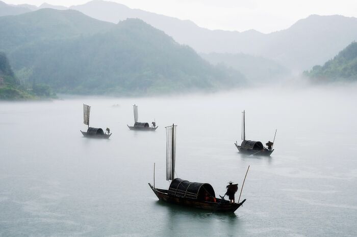 Traditional boats on misty Asian river, capturing the soul of Asia through stunning photography and serene landscapes.