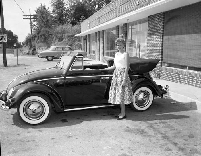 Woman in 1950s skirt standing next to a classic convertible car, capturing everyday life in 1950s Florida.