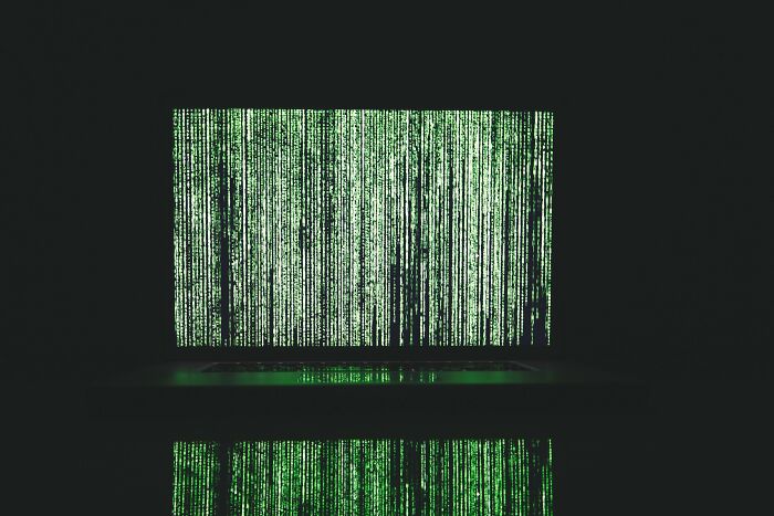 Laptop screen filled with green digital code representing AI manipulation and ChatGPT deception concepts.