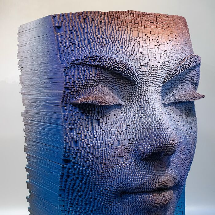 Wooden sticks sculpted into a hypnotic 3D face with intricate textured details and a gradient blue to purple finish.