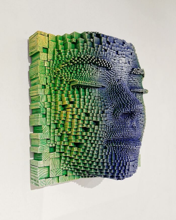 3D wooden face sculpture made from carved sticks, showing a hypnotic and lifelike expression in green and blue tones.
