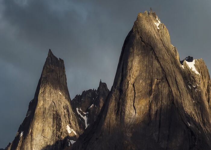 Dramatic landscape shot of jagged mountain peaks with sunlight and shadows, capturing breathtaking fantasy-like scenery.