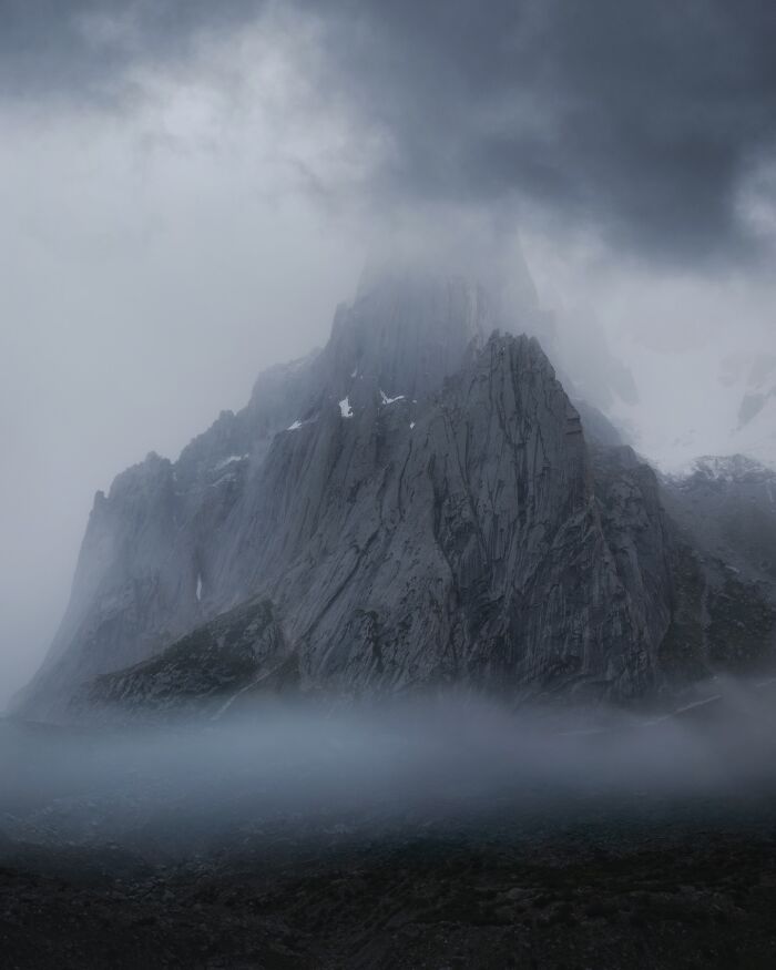Misty mountain landscape with dramatic clouds and fog, a breathtaking scene captured in fantasy-like style photography.