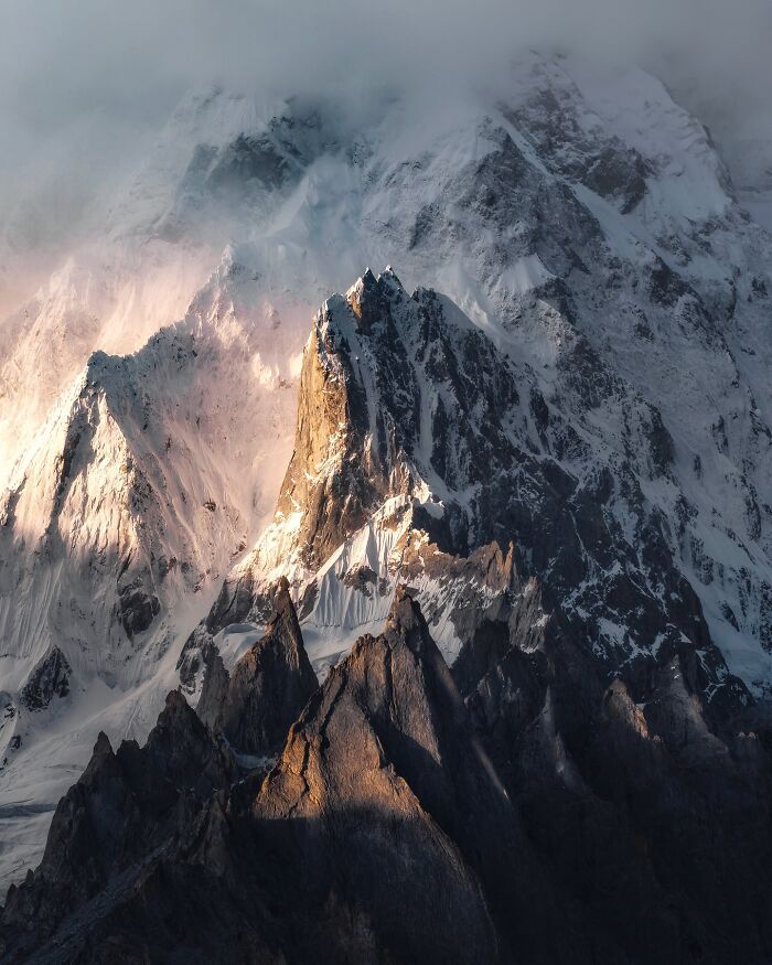 Breathtaking landscape shot of rugged snow-covered mountain peaks resembling a fantasy movie scene in dramatic light.