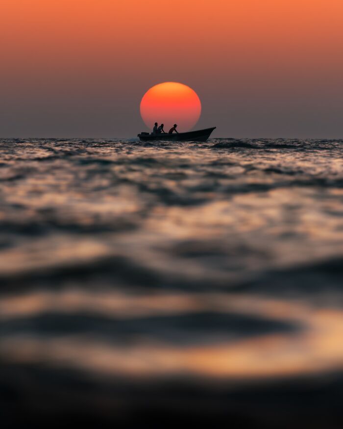 Boat silhouette with two people on the water at sunset in a breathtaking landscape shot resembling a fantasy scene.