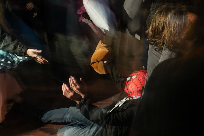Photographer snaps a coincidental public moment of a person in a Spider-Man mask surrounded by blurred people and motion.