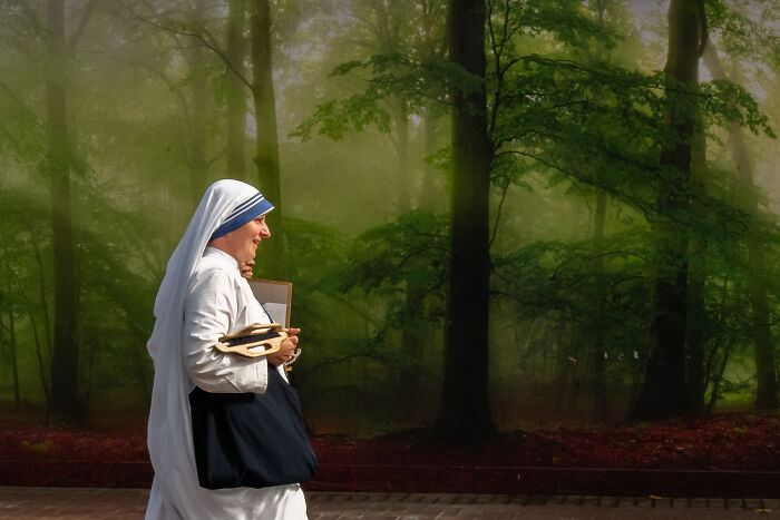 Nun walking through a foggy park holding shoes and a book in a candid shot captured by a photographer snapping coincidental moments in public.