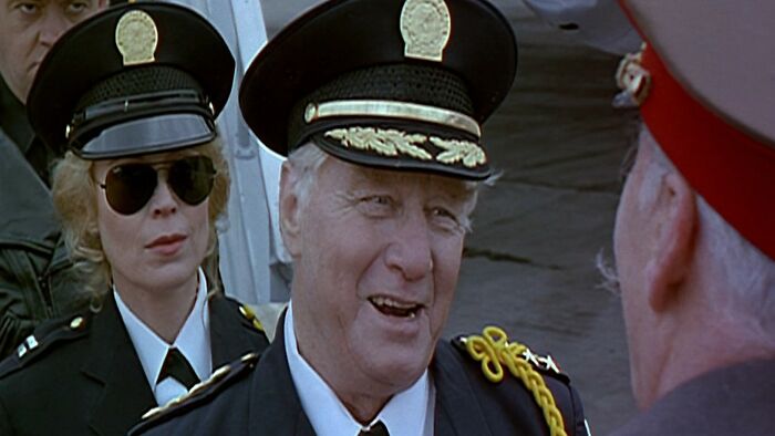 Two police officers in uniform and hats, engaged in conversation, from one of the worst movies of all time.