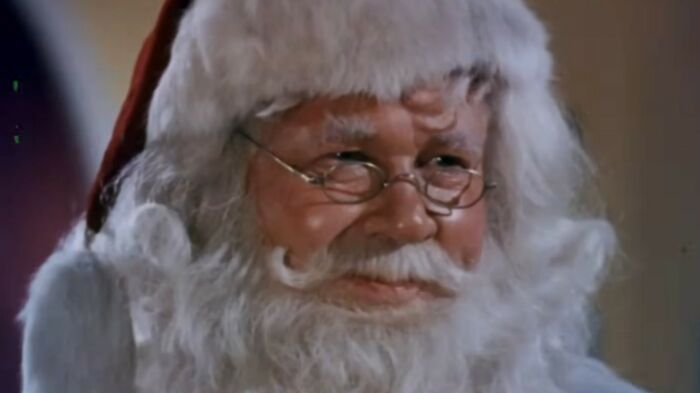 Close-up of a smiling Santa Claus with glasses and a white beard featured in the worst movies of all time list.