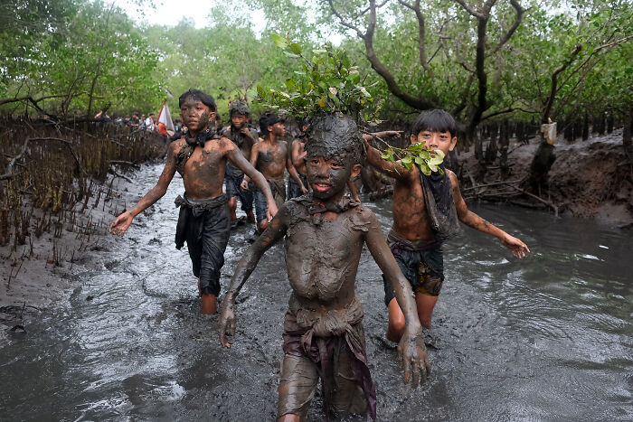 Children covered in mud playing in a mangrove forest during a spectacular mangrove photography awards event.