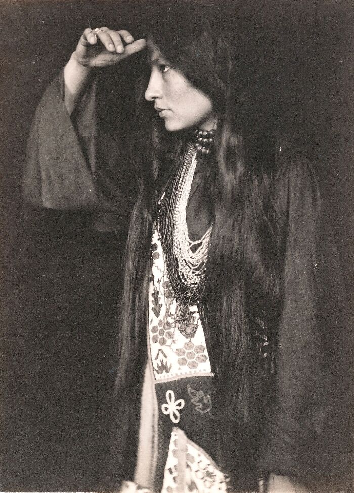 Vintage black and white photo of a woman with long hair and traditional jewelry, embodying timeless beauty.