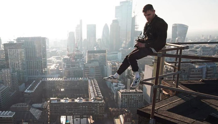 21YO daredevil perched on rooftop edge overlooking city, capturing footage before attempting record-breaking dive stunt. 21YO daredevil perched on rooftop edge overlooking city, capturing footage before attempting record-breaking dive stunt.