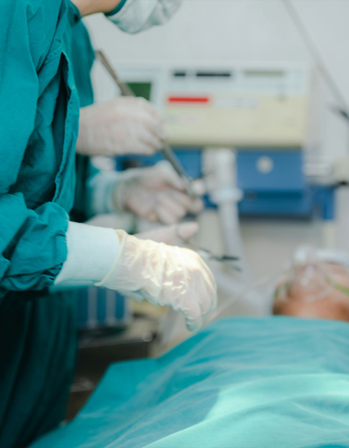 Autopsy tech wearing gloves performing an examination in a medical setting with patient on the table. Autopsy tech wearing gloves performing an examination in a medical setting with patient on the table.