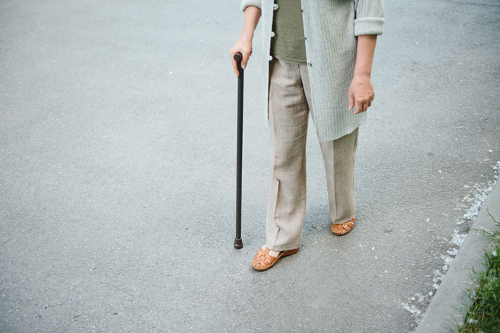 Person using a cane walking on pavement, representing disabled employee facing ableist manager challenges in workplace accommodations.