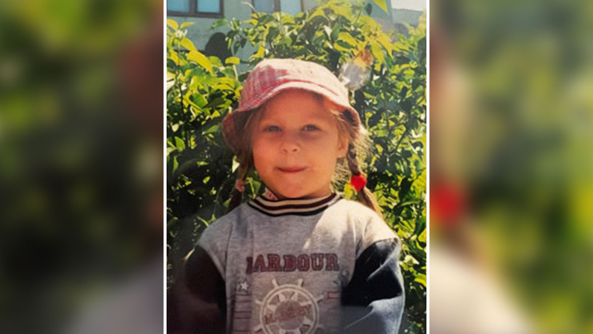Young girl with braided hair and pink hat standing outdoors, representing wholesome and amazing adoption stories.