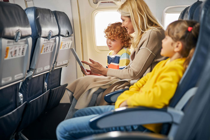 Woman and two children seated inside airplane cabin, highlighting plane passenger upset over seat dispute on flight. Woman and two children seated inside airplane cabin, highlighting plane passenger upset over seat dispute on flight.