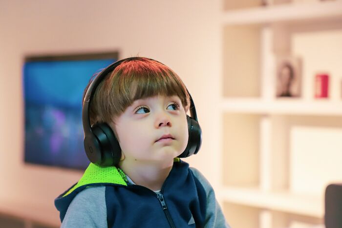 Young child wearing headphones indoors, illustrating bizarre beliefs people still fall for despite science busting myths.