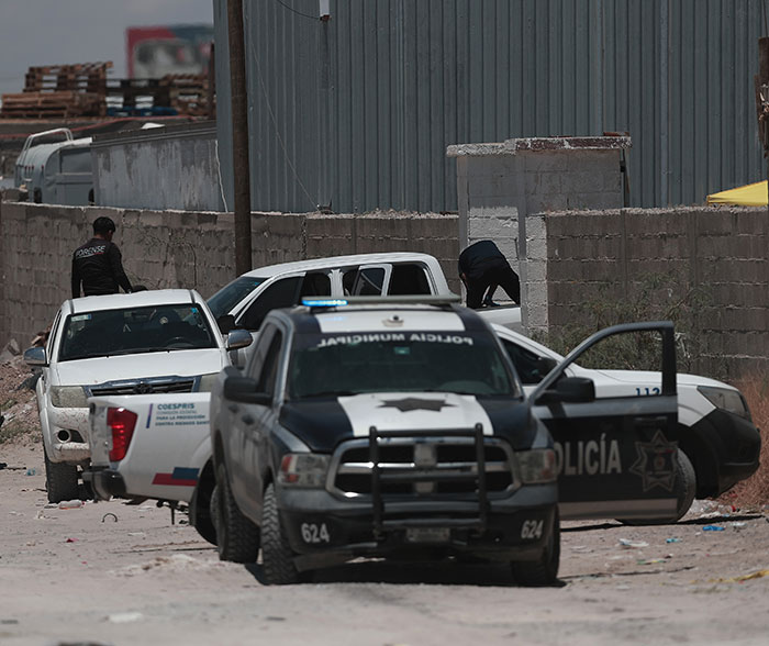 Police vehicles and officers at a dusty site investigating nearly 400 human bodies stacked inside a mysterious building. Police vehicles and officers at a dusty site investigating nearly 400 human bodies stacked inside a mysterious building.