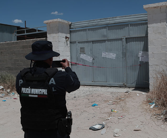 Police officer taking photo of a sealed building suspected to contain nearly 400 human bodies stacked inside. Police officer taking photo of a sealed building suspected to contain nearly 400 human bodies stacked inside.