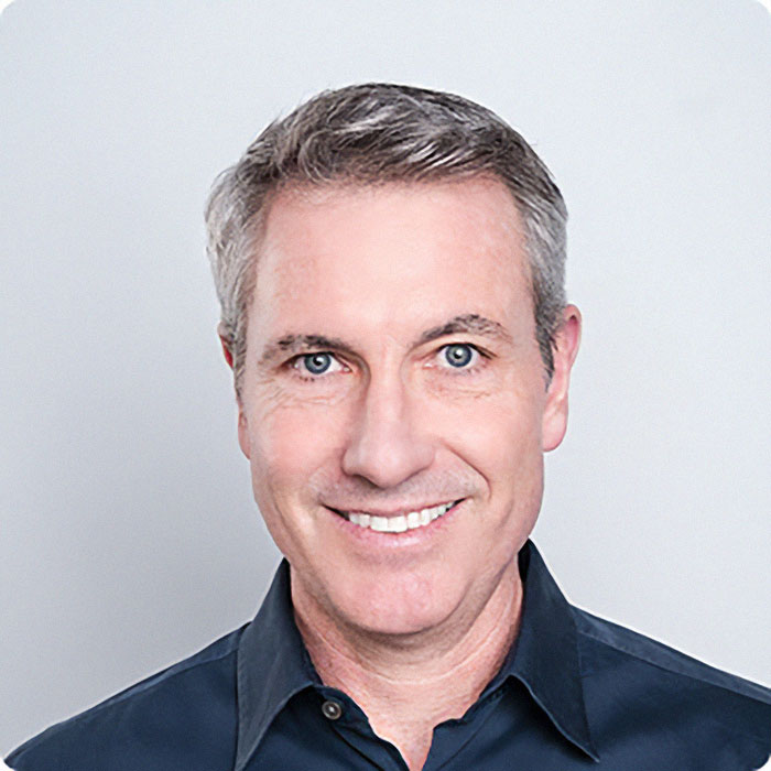 Middle-aged man with gray hair smiling, wearing a dark shirt, representing the wife of CEO accused of cheating scandal Middle-aged man with gray hair smiling, wearing a dark shirt, representing the wife of CEO accused of cheating scandal