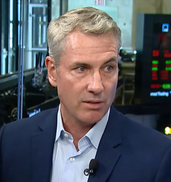 Man in a navy blazer and light blue shirt speaking during an interview about viral Coldplay couple behavior before Chris Martin caught them. Man in a navy blazer and light blue shirt speaking during an interview about viral Coldplay couple behavior before Chris Martin caught them.