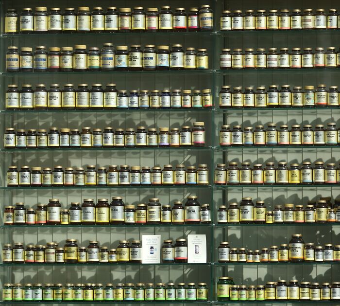 Glass shelves filled with numerous vintage medicine bottles representing bizarre beliefs people still fall for despite science.