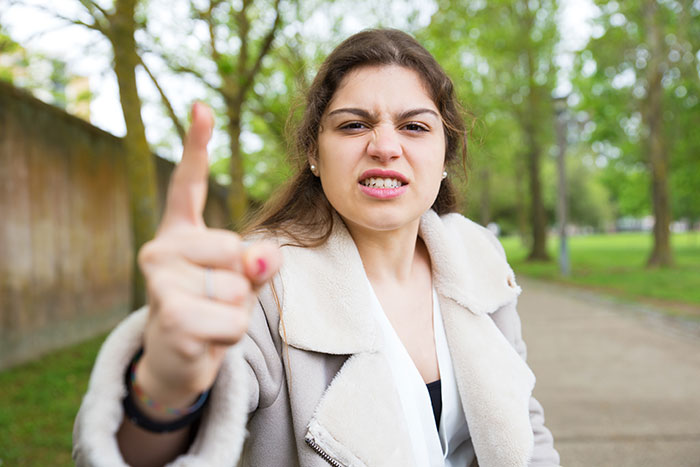 Angry young woman outdoors pointing finger, expressing frustration related to racist switch and family conflict. Angry young woman outdoors pointing finger, expressing frustration related to racist switch and family conflict.