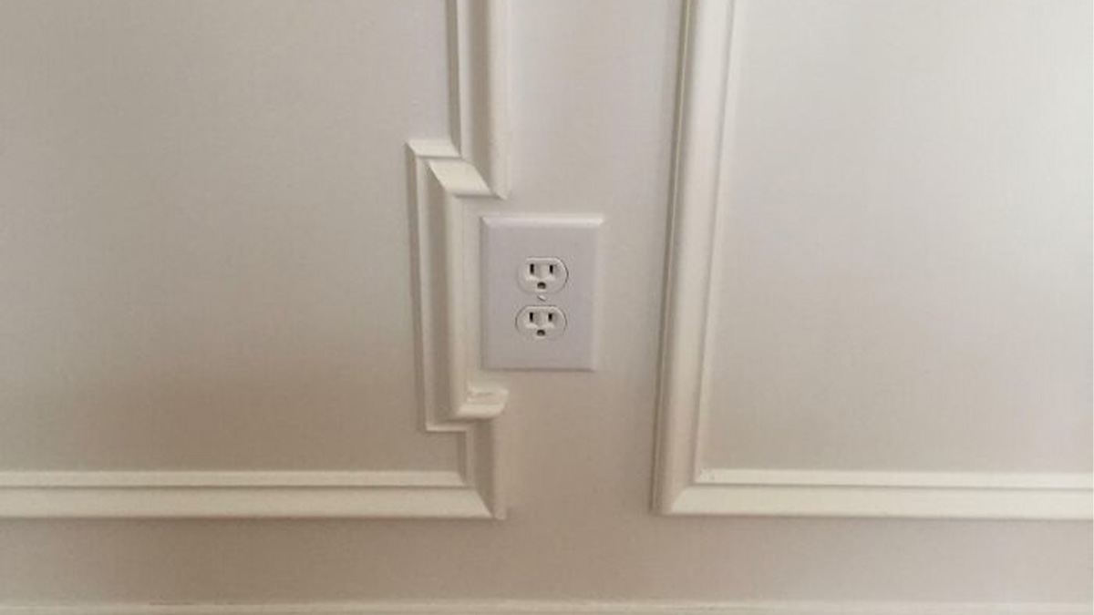 Wall outlet misaligned with decorative molding edges, an imperfect detail that might annoy people with OCD tendencies.