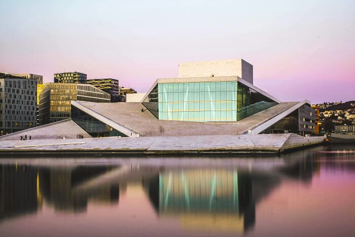 Modern architectural building with glass and concrete reflected in water, representing smartest countries shaping the future.