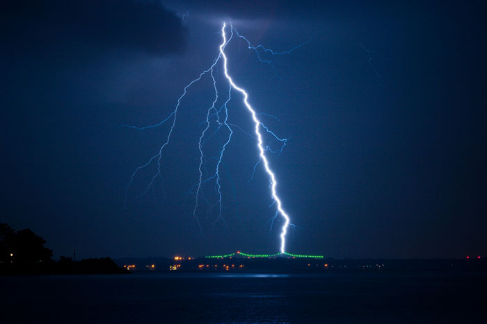 Lightning strike over a dark lake at night symbolizing the tragic death of Olympic medalist skier in a storm. Lightning strike over a dark lake at night symbolizing the tragic death of Olympic medalist skier in a storm.