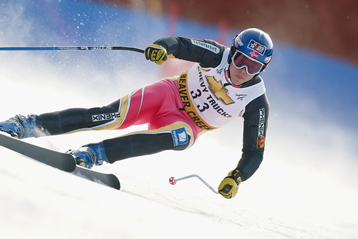 Olympic medalist skier racing downhill in full gear during a competitive skiing event on a snowy slope. Olympic medalist skier racing downhill in full gear during a competitive skiing event on a snowy slope.