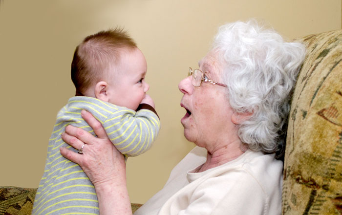 Elderly woman holding baby with gold stud earrings after unlicensed ear piercing during family visit. Elderly woman holding baby with gold stud earrings after unlicensed ear piercing during family visit.