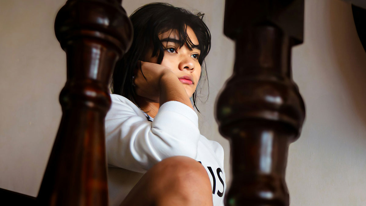 Young woman with contemplative expression sitting indoors with a focus on makeup and Sephora experience.