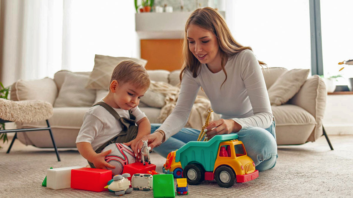 Young woman babysits nephew at home, engaging in play with toys and encouraging his learning environment.