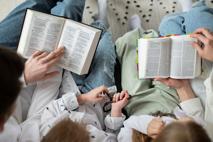 Two adults and two children reading the Bible together while babysitting nephews in a cozy setting. Two adults and two children reading the Bible together while babysitting nephews in a cozy setting.