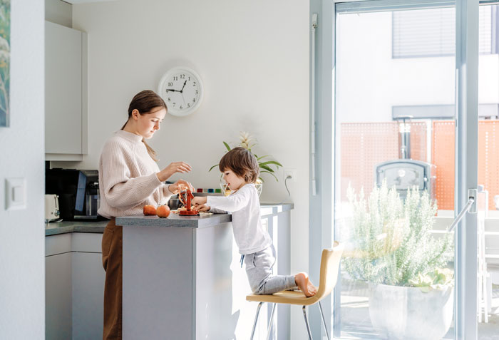 Woman and child in bright kitchen, emphasizing neighbor won’t babysit undisciplined kid scenario. Woman and child in bright kitchen, emphasizing neighbor won’t babysit undisciplined kid scenario.
