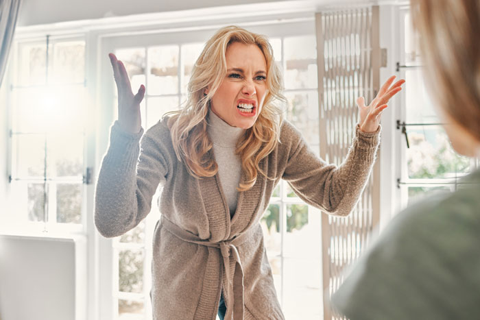 Angry woman raising hands indoors, expressing frustration during a heated argument about babysitting undisciplined kid. Angry woman raising hands indoors, expressing frustration during a heated argument about babysitting undisciplined kid.