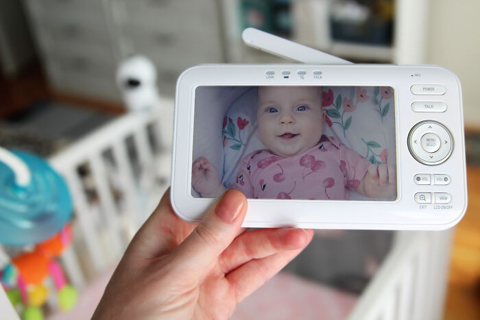 Baby monitor showing smiling baby in crib, related to creepy babysitter stories for a chilling childcare experience.