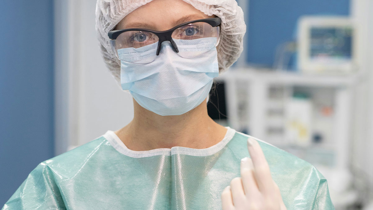 Surgeon wearing protective gear and gloves preparing for a facelift procedure in a medical setting.