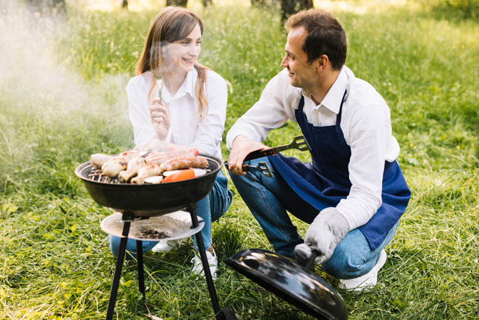 Couple enjoying outdoor barbecue, with man grilling and woman holding fork, hinting at a shocked bestie and possible hidden affair. Couple enjoying outdoor barbecue, with man grilling and woman holding fork, hinting at a shocked bestie and possible hidden affair.