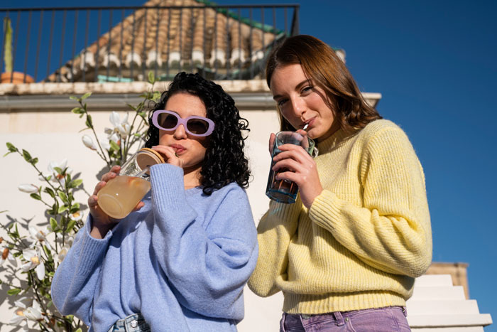 Two women enjoying drinks outside on a sunny day, highlighting a wannabe influencer and friendship conflict. Two women enjoying drinks outside on a sunny day, highlighting a wannabe influencer and friendship conflict.