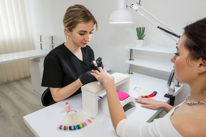 Woman getting nails done in a studio, highlighting a scene involving a wannabe influencer and studio party conflict. Woman getting nails done in a studio, highlighting a scene involving a wannabe influencer and studio party conflict.