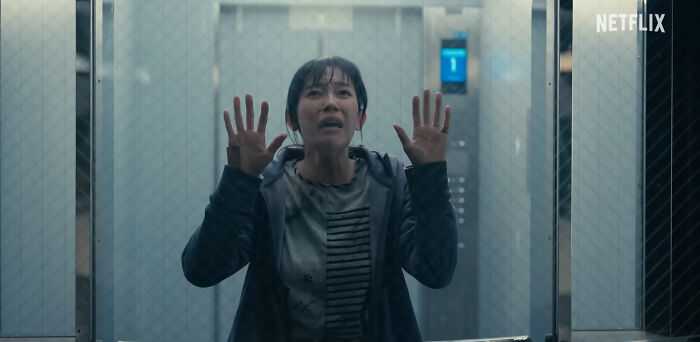 Woman with hands pressed on glass, anxious and trapped, in a scene from one of the best Netflix shows trending among netizens.