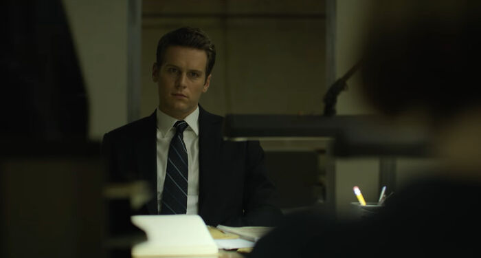Man in a suit and tie sitting in an office, scene from one of the best Netflix shows that keep viewers coming back