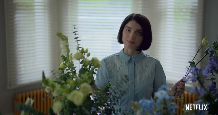 Young woman arranging flowers indoors, representing best Netflix shows that keep viewers coming back for more.
