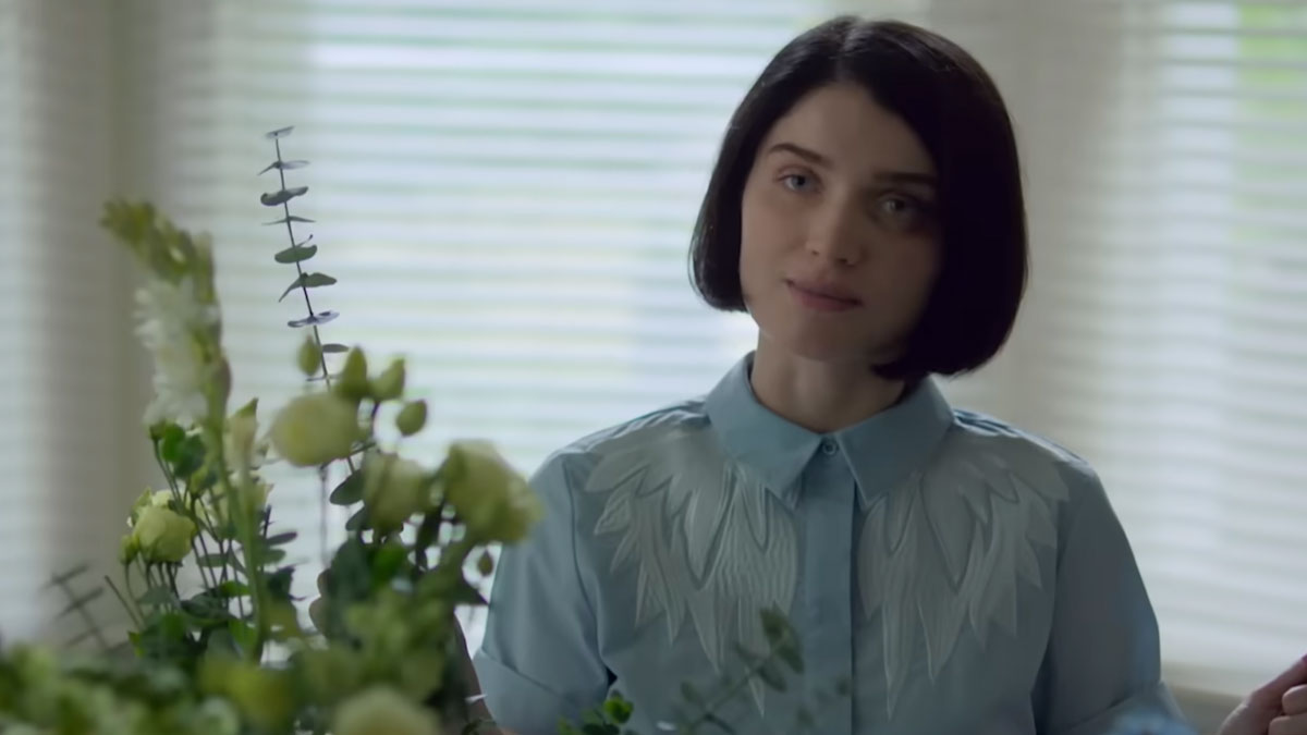 Young woman with short dark hair and blue shirt arranging flowers indoors, representing popular Netflix shows fans keep watching.